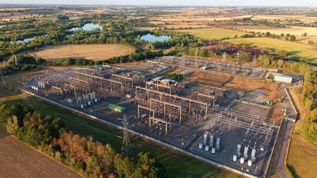 Aerial view of Grendon national grid station with electrical transformers and power lines surrounded by rural fields and trees in Northampton, England, United Kingdom.