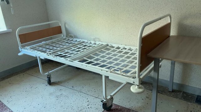 Empty hospital room with an adjustable patient bed beside a small bedside table