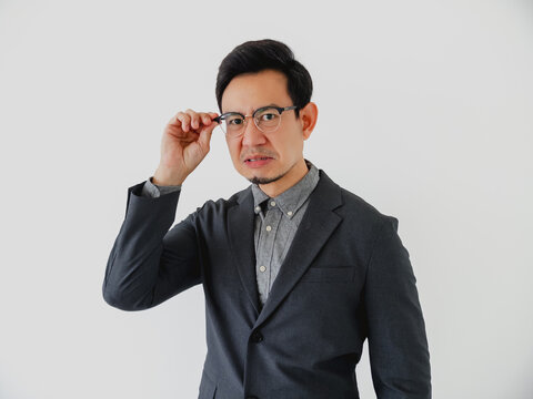 Confused Asian Businessman Adjusting Glasses with a Skeptical Expression on a White Background