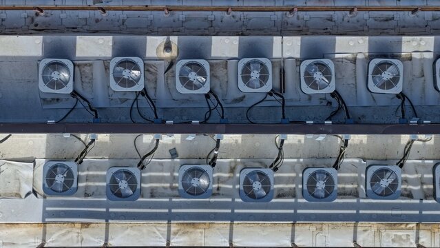 Aerial view of multiple HVAC air conditioning units arranged in rows on a flat commercial rooftop in Boulder, Colorado, United States.