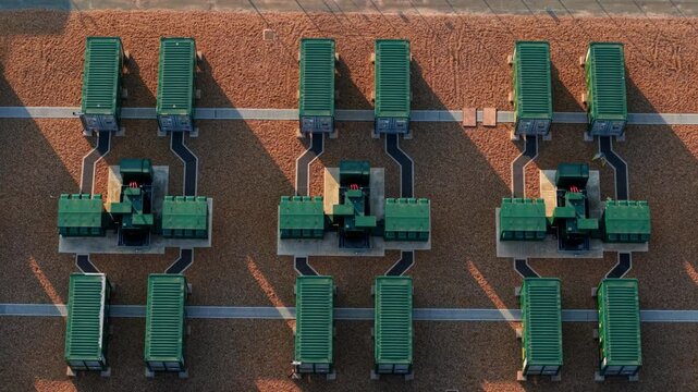 Aerial view of Grendon national grid battery storage systems with rows of green containers on gravel ground during golden hour in Northampton, England, United Kingdom.