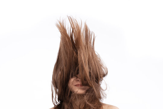 Woman with long hair standing with hair lifted upward against white background