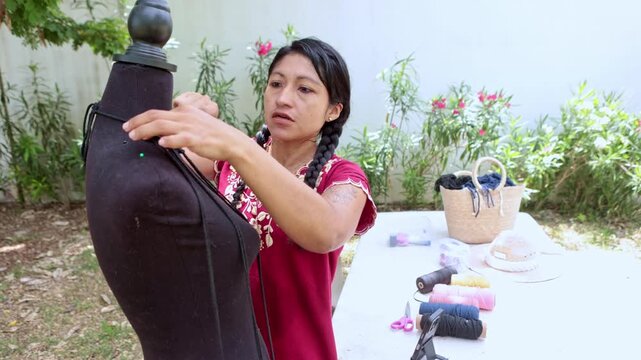 Mexican artisan woman creating a macrame design on a mannequin outdoors