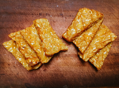 Sliced fried tempeh or tempe on a plate, traditional Indonesian soybean food on wooden board