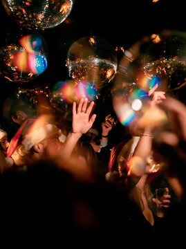 Group of young people partying at Christmas event dancing with transparent balloons and festive lighting