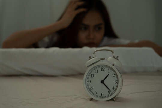 asian woman in bed late trying to sleep suffering insomnia, sleepless or scared in a nightmare, looking sad worried and stressed. Tired and headache or migraine waking up in the middle of the night.