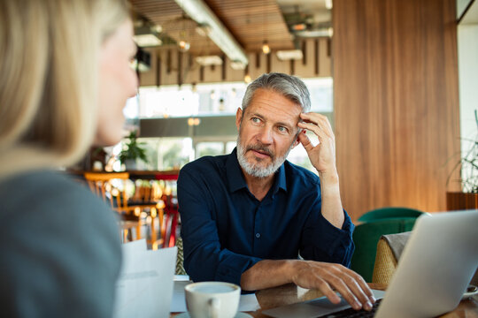 Mature man listening to colleague in cafe meeting