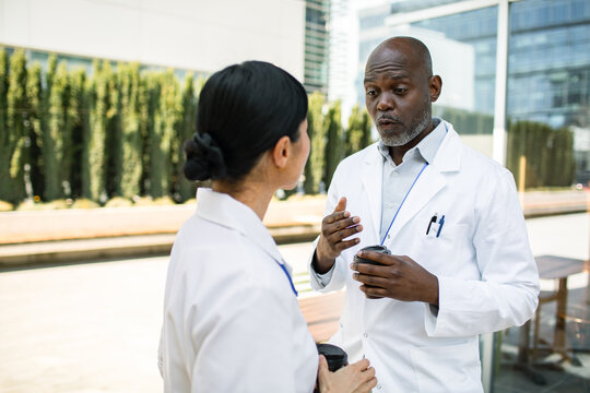 Two doctors talking over coffee outside a hospital