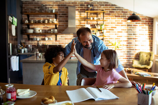 Kids high five during homework at kitchen table