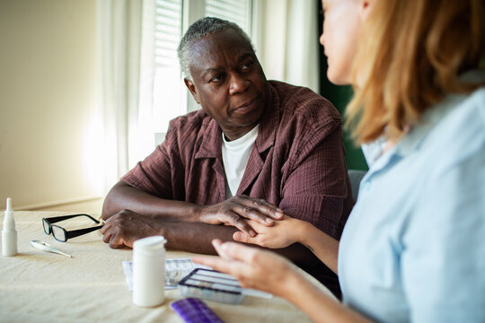 Caregiver explains medication to senior man at home