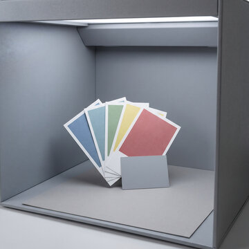 Packaging color swatches propped upright in a tabletop color-matching light booth