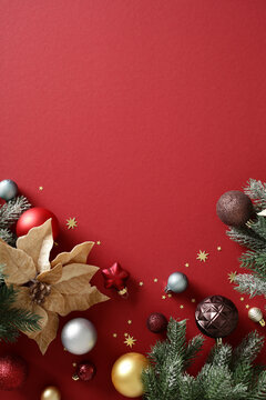 Christmas baubles and poinsettia on red background with copy space