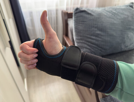 Black wrist support brace worn on hand indoors
