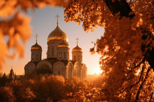 Orthodox church with golden domes standing among colorful autumn trees at golden hour