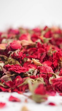 Close up cinematic panning shot of dried red rose buds and petals for herbal tea and aromatherapy.