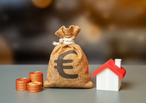 A euro money bag and a house figurine. Investments, buying and selling. Rental income. Property taxes. Mortgage for purchasing a house.