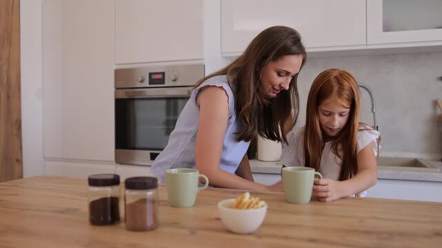 Mother and daughter making coffee and hot cocoa in the kitchen