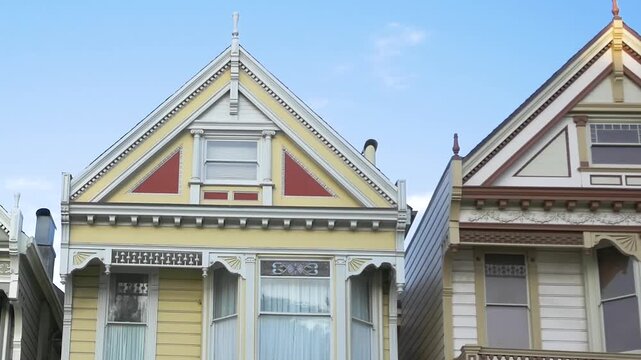 Aerial view of a yellow Victorian house with ornate woodwork and red accents in San Francisco, California, United States.