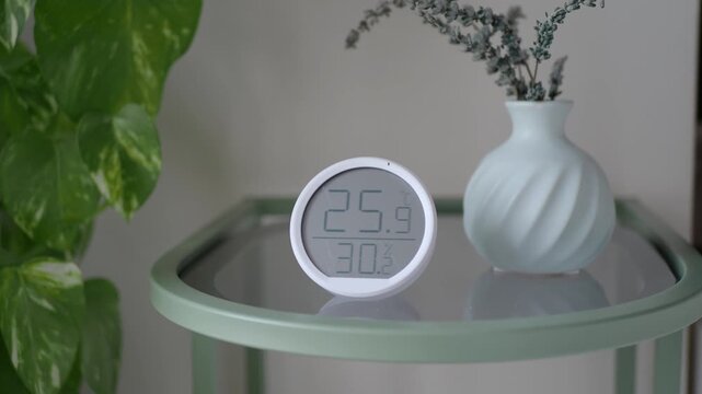 A close-up view of a smart home thermometer showing temperature and humidity levels, capturing the device's clear display and modern design in a static shot.