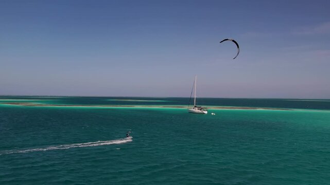 Aerial view of a kitesurfer gliding across the turquoise waters of the Los Roques archipelago, Los Roques, Dependencias Federales, Venezuela.