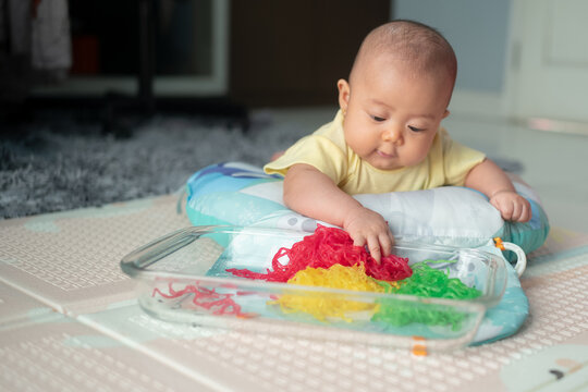 Curious Asian Baby Touching Colorful Noodles in Glass Dish During Tummy Time Sensory Activity