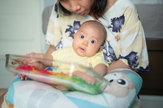 Cute Asian Baby Looking at Camera During Sensory Play Activity with Mother and Colorful Noodles