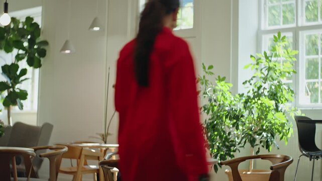 Women collaborate on a laptop during a business meeting at a bright coworking cafe table, smiling and talking as they review work together in a relaxed indoor workspace.