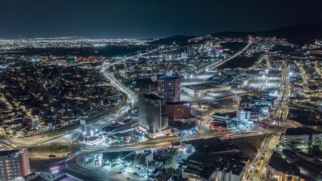 Aerial view of Torre Tangente 52 SLP illuminated at night with surrounding urban lights, highways, and city buildings in San Luis Potosi, San Luis Potosi, Mexico.