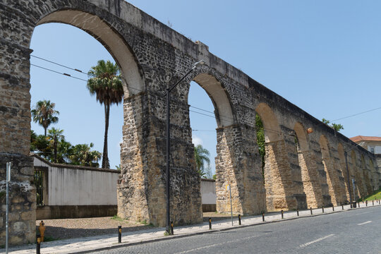 Stone aqueduct arches beside a cobblestone road