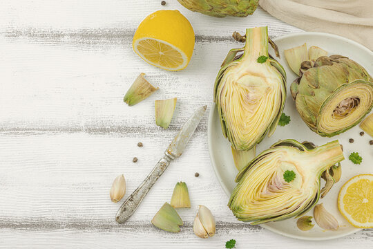 Fresh green artichokes cooking on wooden background. Traditional seasonal ingredients