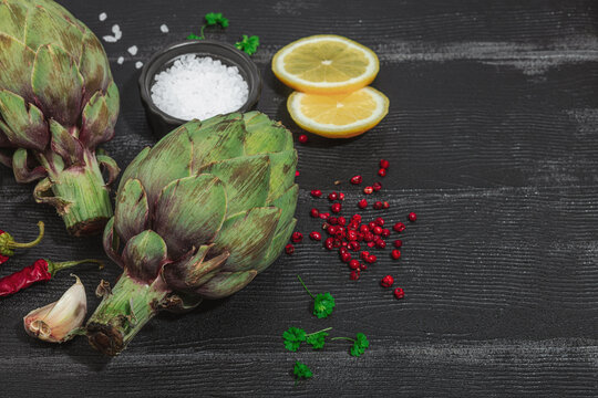 Fresh green artichokes cooking on wooden background. Traditional seasonal ingredients