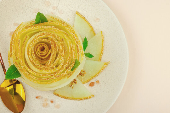 Elegant melon carpaccio dessert shaped a flower, garnished with mint, spices, pink salt crystals