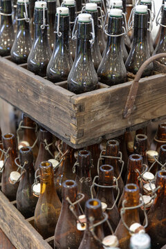Vintage Glass Bottles With Swing Top Closures In Wooden Crates Brown And Clear Glass Rustic Appearance Stacked For Storage Or Display