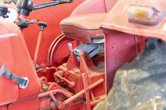 Close-Up Of A Red Vintage Tractor With Seat Steering Wheel And Mechanical Components For Agricultural Or Transportation Concepts