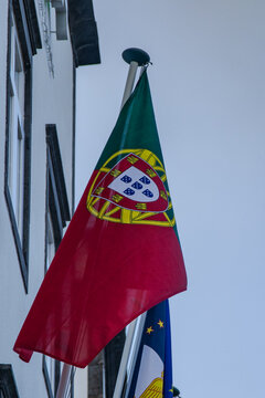 Primer plano de la bandera nacional de Portugal izada en la fachada de un edificio institucional junto a la bandera auton&oacute;mica de las Azores.