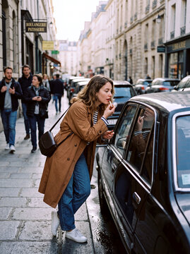 Young Woman Applying Lipstick Using Car Window Reflection on Paris Street   