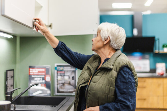 Older Woman Opening Cabinet in Kitchen Display