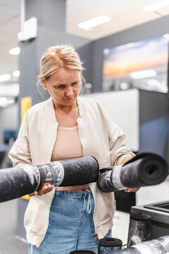 Woman Examining Rolled Flooring Material in Home Improvement Store