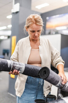 Woman Examining Rolled Flooring in Home Improvement Store