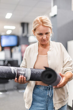 Woman Examining Rolled Material in Home Improvement Store