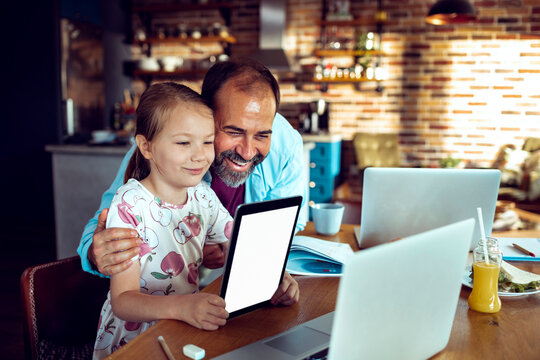 Man and girl holding blank screen tablet at home