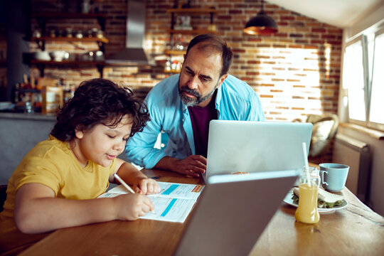 Man helping boy with homework at kitchen table