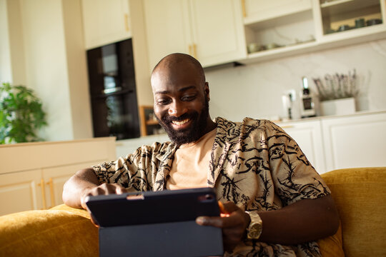 Smiling man using tablet on sofa at home