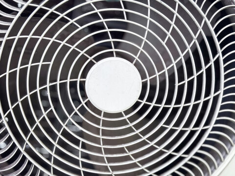 Close-up of an air conditioner outdoor unit fan grille and abstract spiral pattern texture