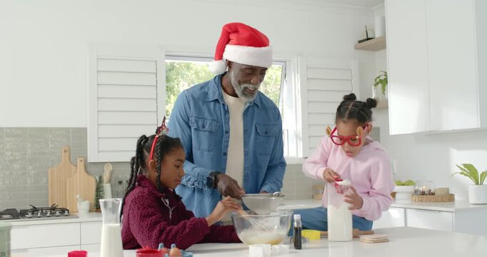 African family in Santa hat using sifter, whisking, measuring into glass bowl for christmas baking