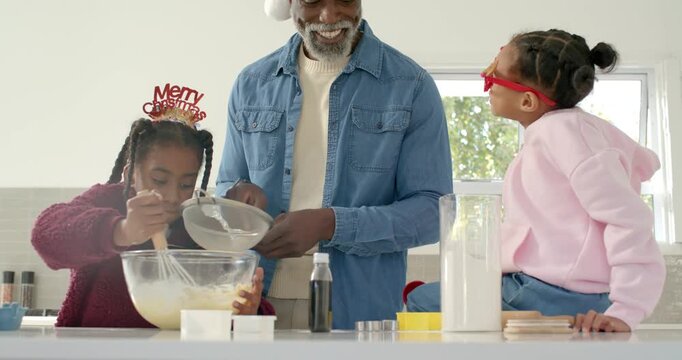African American family starting christmas baking home counter senior man pouring children whisking