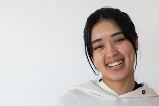 Asian African-American woman smiling facing camera on wall wearing snap-button hoodie, copy space