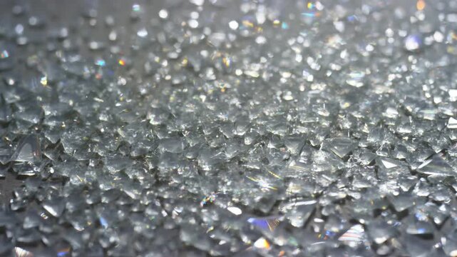Transparent glass shards shimmering across a reflective surface as colorful light shifts