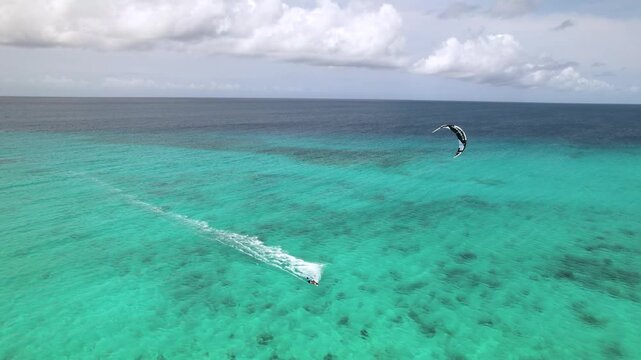 Aerial view of a kitesurfer gliding across the turquoise waters of the Los Roques archipelago in Los Roques, Dependencias Federale, Venezuela.
