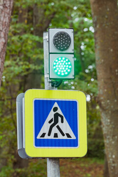 Green Pedestrian Crossing Signal Beside Road Sign